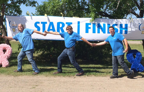 Convergint day Regina male colleagues holding hands during group photo