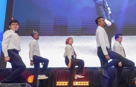 Eight people on stage with their hands in the air