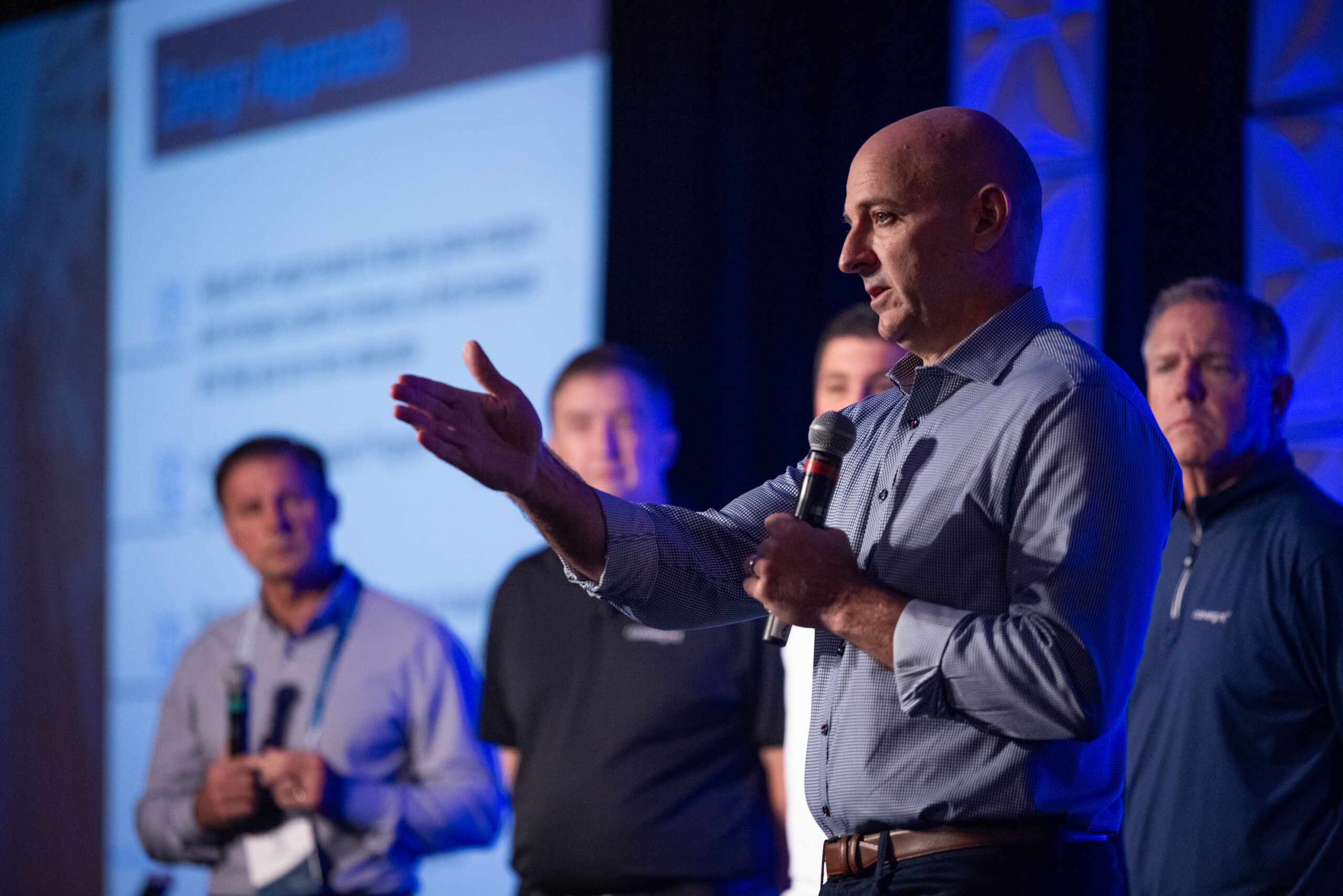 A man holding a microphone and gesturing to the crowd